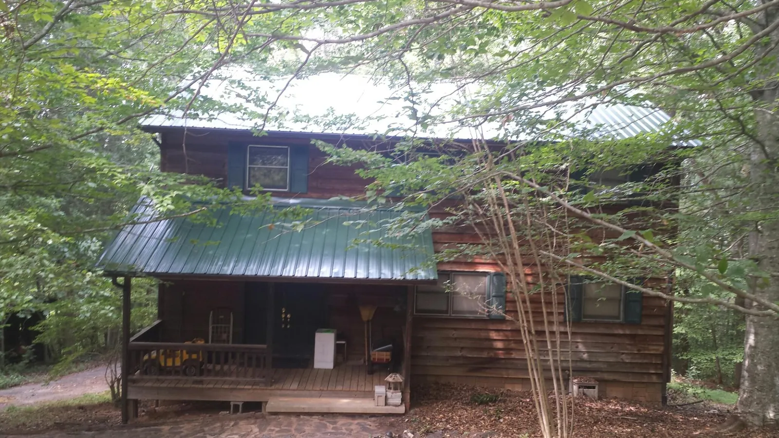 Green metal roof and covered porch on a log cabin in Luckey