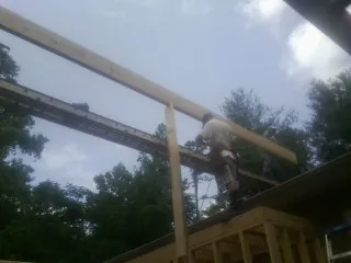 Carpenter setting a ridge beam over a new addition frame — Ice Dam Removal by Roofing Brothers in Luckey