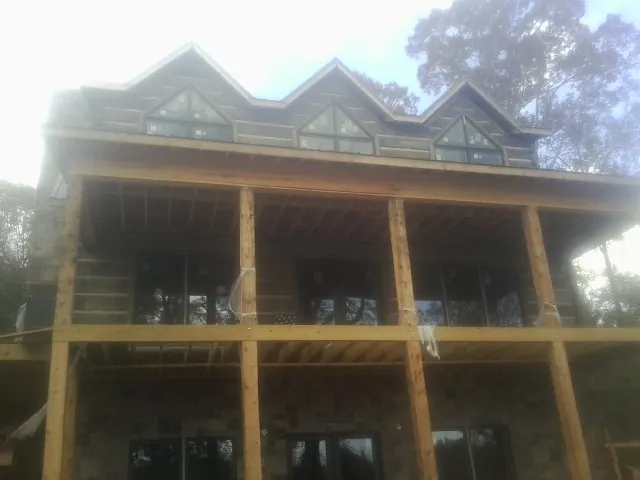 Dormers and porch framing on a large log home under construction — Roof Coating work by our crew in Luckey