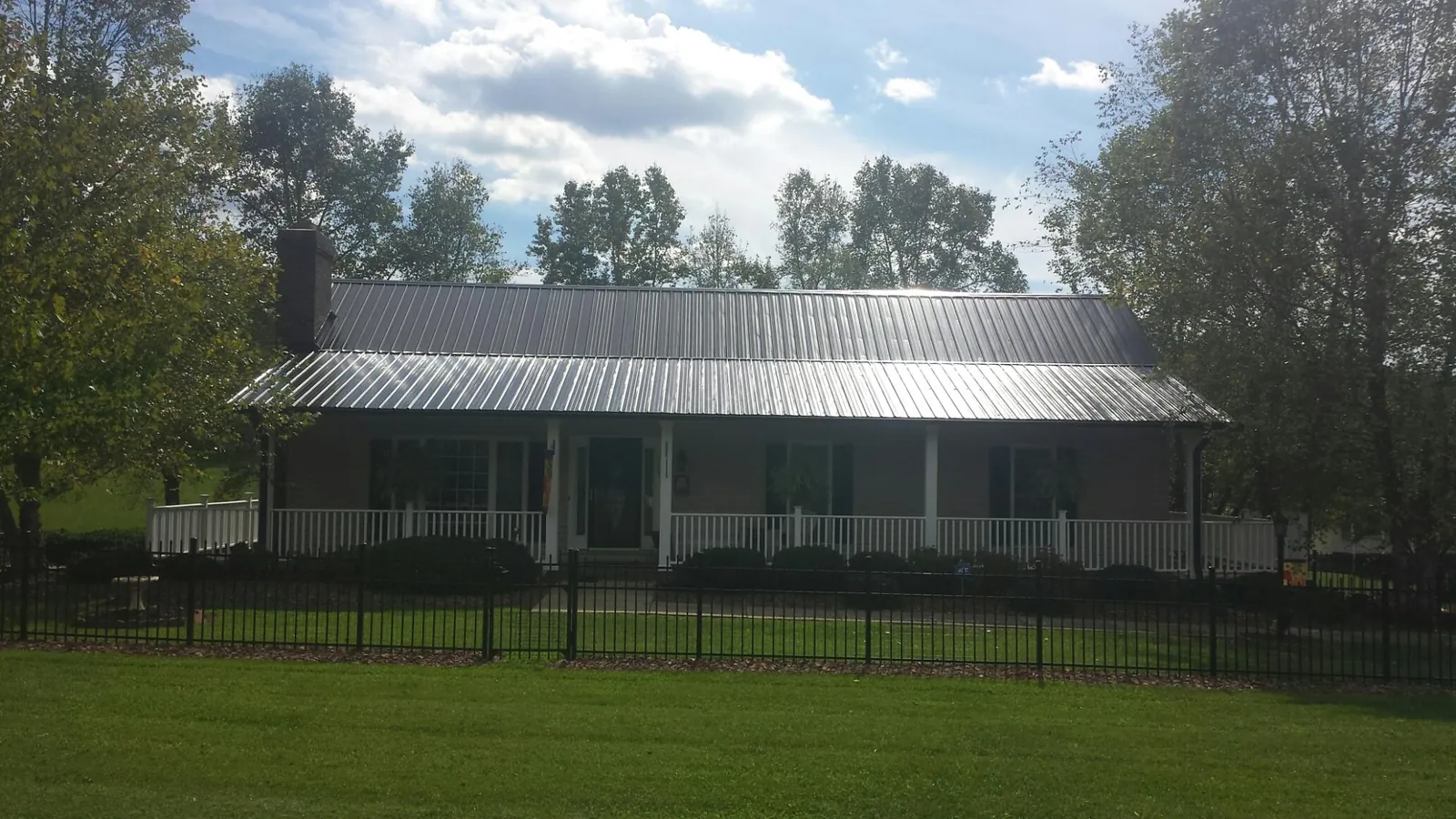 Gray metal roof on a brick ranch with a full width front porch — Gutter Guard Installation work by our crew in Luckey