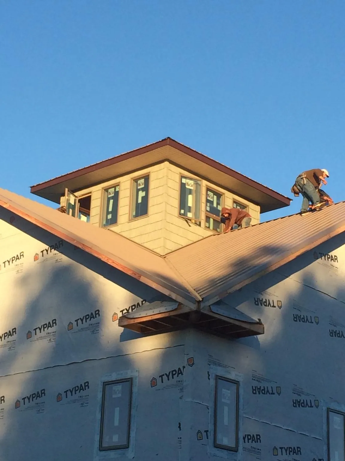 Roofers working around a rooftop cupola on a new metal roof at sunset — Roof Waterproofing in Luckey by Roofing Brothers